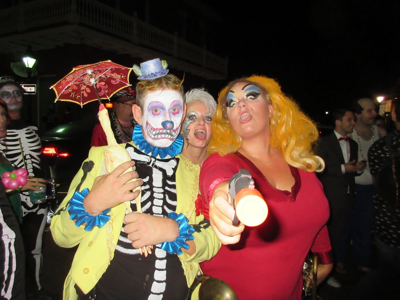 Costumed revelers in skeleton makeup and a blonde wig on a New Orleans street at night